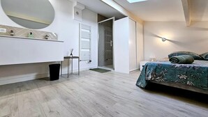 A modern bedroom with a skylight, a large mirror, a bedside table, and a bed with a floral bedspread.