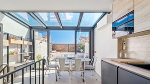 A modern kitchen with a glass dining area, a wooden countertop, and a view of the outside.