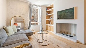 A modern living room with a grey sectional sofa, a round coffee table, a fireplace, and a large painting on the wall.