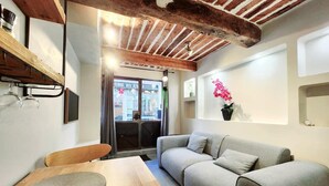 Une pièce chaleureuse avec un plafond en bois, un canapé gris, une table en bois et une fenêtre donnant sur l’extérieur.