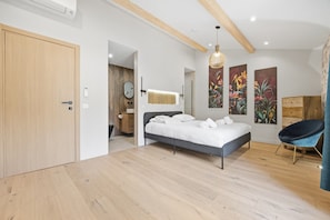 Une chambre à coucher moderne avec un lit, une chaise et des œuvres d’art accrochées aux murs.