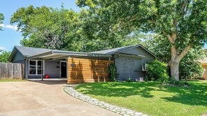 A modern single-story house with a covered porch, a brick exterior, and a stone pathway leading to the front door. - Robin House with two master suites! (Burleson)
