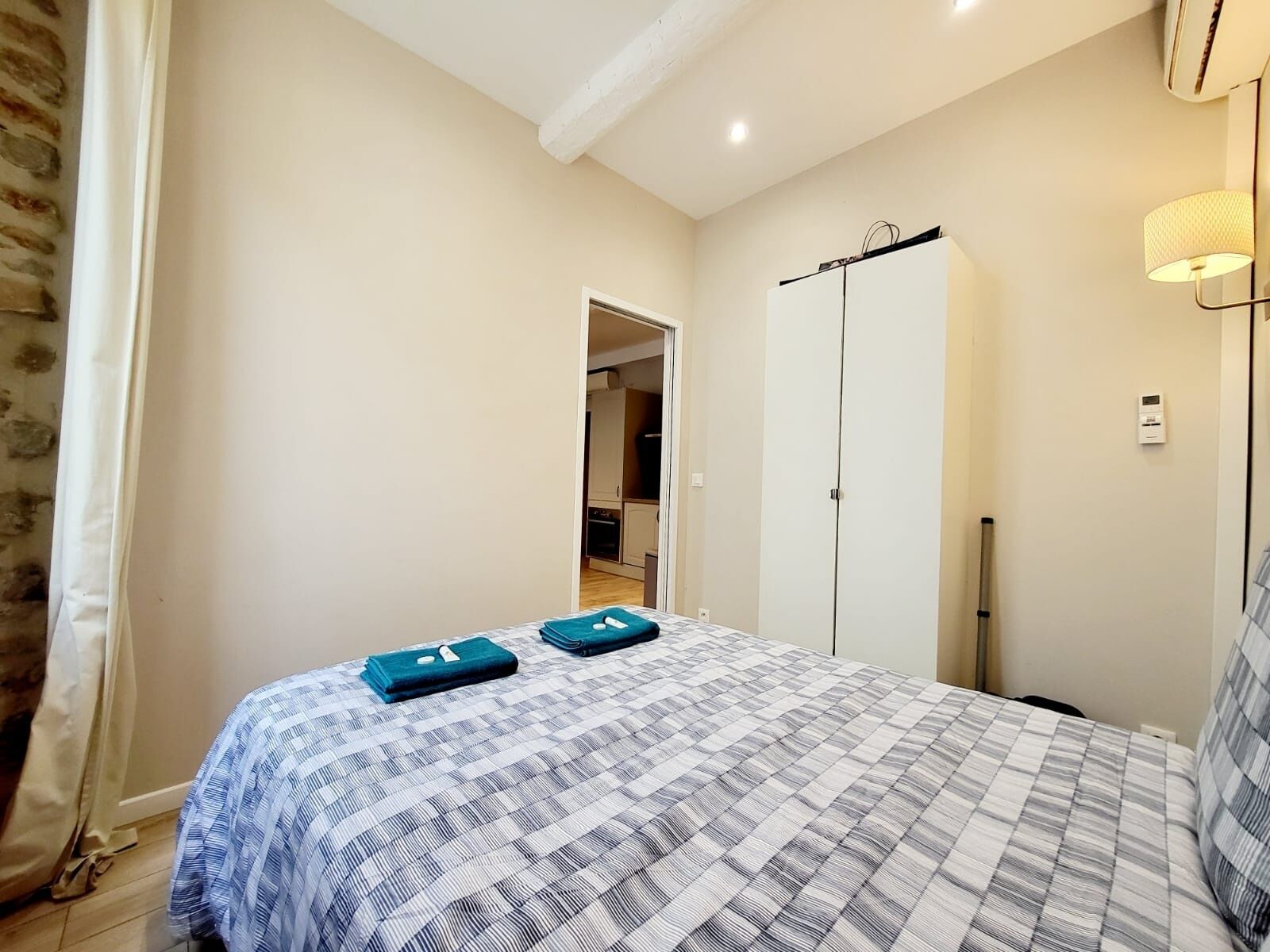 Ein Schlafzimmer mit Bett, Kleiderschrank, Lampe und einer Tür zu einem anderen Raum.