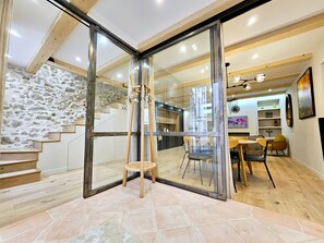 Interior moderno com divisória de vidro, escada de madeira e sala de jantar com cadeiras e mesa.