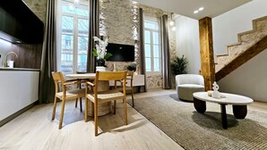 A modern living room with a dining area, a flat-screen TV mounted on the wall, a staircase, and a kitchen area with a sink and countertop. - Le Lacan - Proche du Port (Antibes)