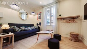 Una sala de estar moderna con un sofá, un espejo redondo, una mesita y una planta colgante.