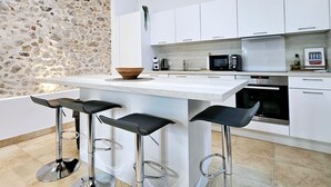 A modern kitchen with a stone accent wall, white cabinetry, a central island with bar stools, and a skylight.