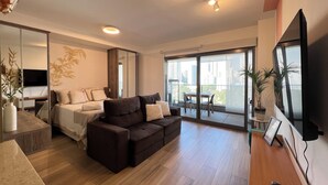 Una sala de estar moderna con un sofá marrón oscuro, un televisor de pantalla plana y un comedor con una mesa y sillas.