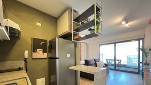 Una cocina moderna con refrigerador empotrado, una encimera y un comedor con sofá y mesa.
