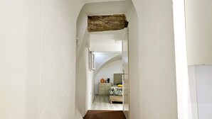 A narrow hallway with a brown hexagonal tile floor, white walls, and a wooden beam ceiling. - L'Hacienda RDC - climatisé proche de la plage (Antibes)