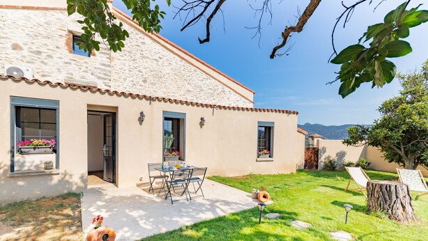 A house with a tiled roof, a patio with a table and chairs, and a garden with a tree stump and a lamp post. - El Capoll - Climatisé, vue montagne (Joch)