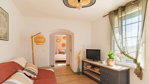 A bedroom with a bed, a desk, a television, and a window with curtains. - El Capoll - Climatisé, vue montagne (Joch)