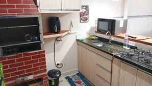 A compact kitchen with a brick oven, a microwave, and a gas stove.