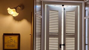 A room with a double door and a wall-mounted light fixture. - Giuliana and Nino's Nest. (Carloforte)