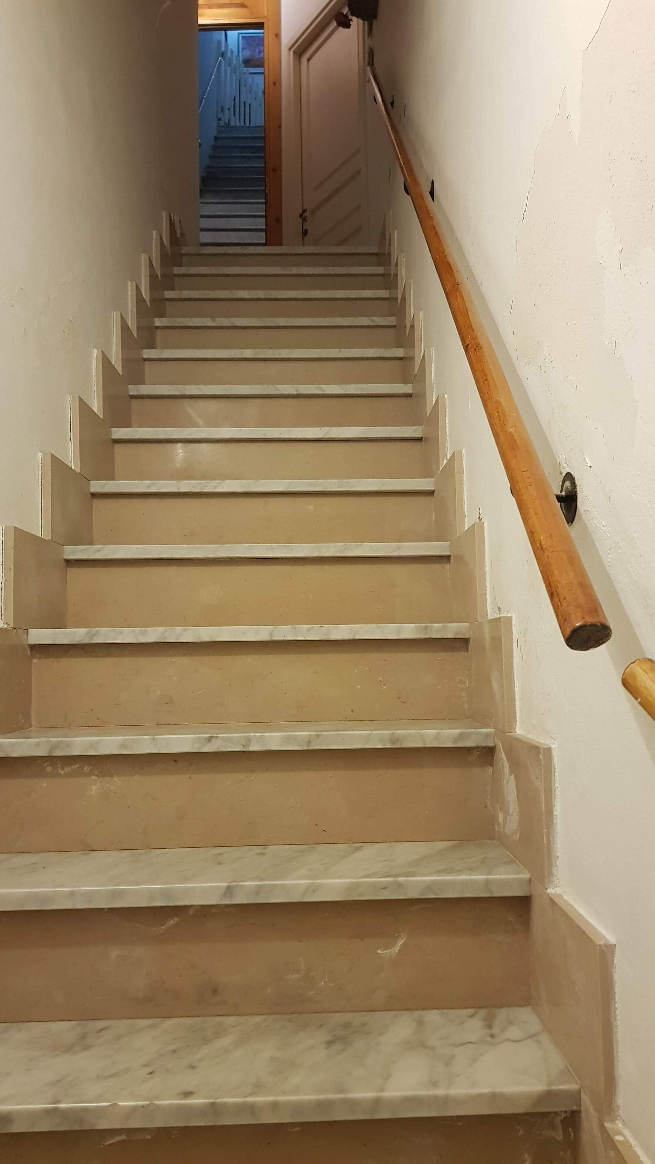 A staircase with beige steps and white handrails.