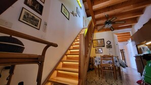 A wooden staircase with illuminated steps, a ceiling fan, and framed pictures on the walls. - Giuliana and Nino's Nest. (Carloforte)