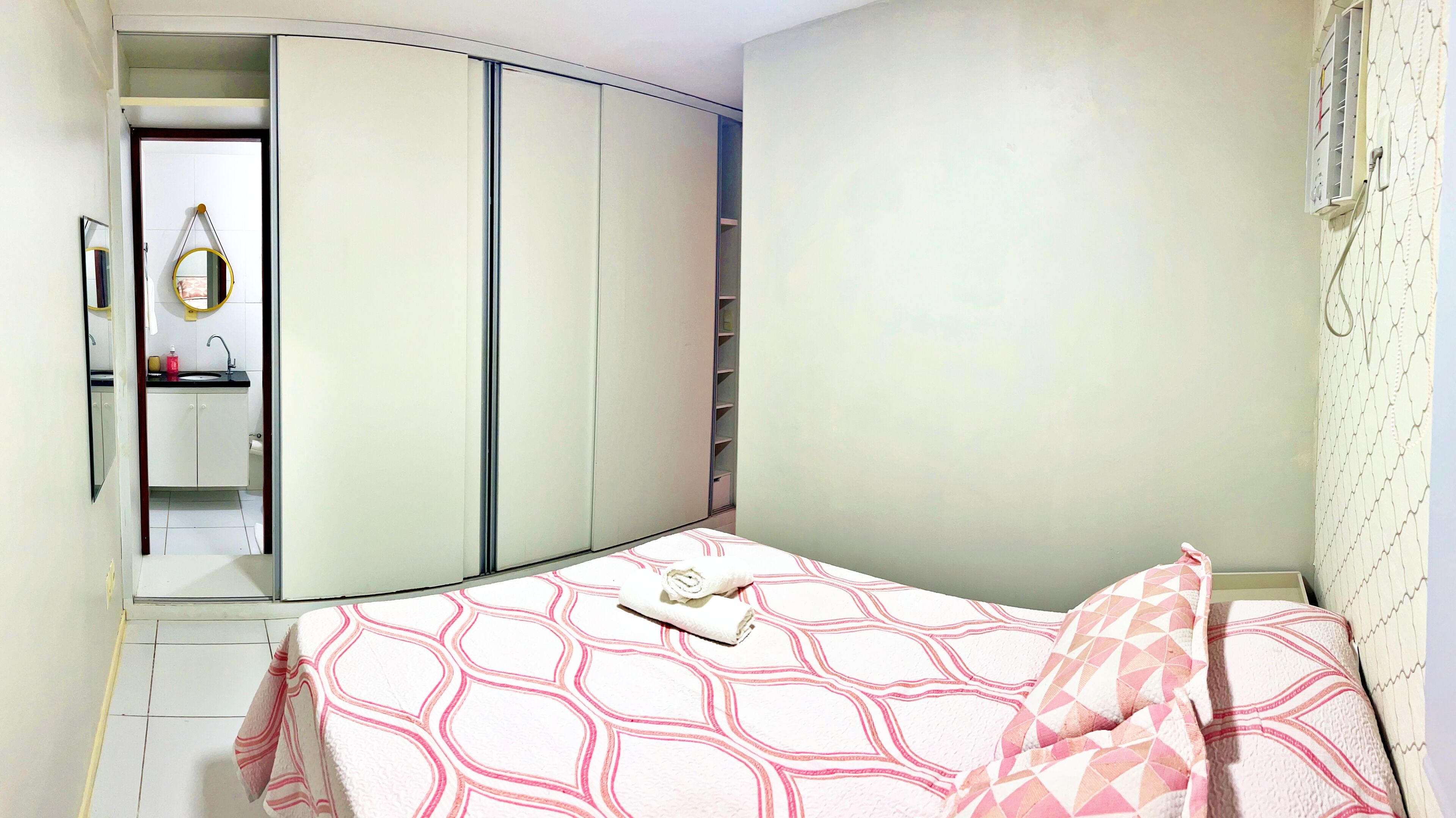 A bedroom with a bed, a wardrobe, and a small bathroom.