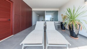 Un interior moderno con dos sillones, una puerta corredera roja y plantas en macetas.