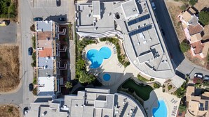 Vista aérea de un complejo turístico con varias piscinas, un patio central y diversas edificaciones.