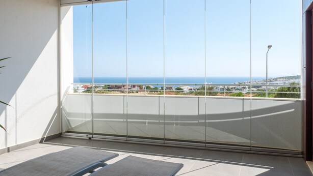 Un balcón con vista despejada al mar y un horizonte urbano distante.
