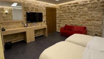 Un dormitorio con cama, televisor, escritorio y sofá rojo.