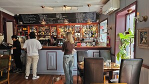 A bar area with a variety of liquor bottles, a menu board, and seating for patrons. - 4BR in oldtown, just steps from opera, Munch, beaches, cafes, shops & local eats (Oslo)