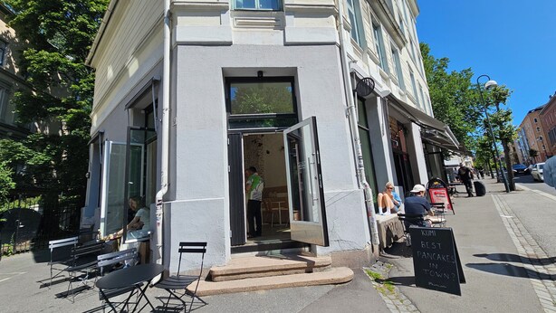 A building with a storefront, outdoor seating, and a signboard. - 4BR in oldtown, just steps from opera, Munch, beaches, cafes, shops & local eats (Oslo)
