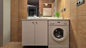 A compact laundry area with a washing machine, a sink, and cabinets.