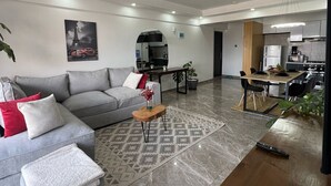 Een moderne woonkamer met een grijze bank, een houten salontafel en een kamerbreed tapijt met een patroon.