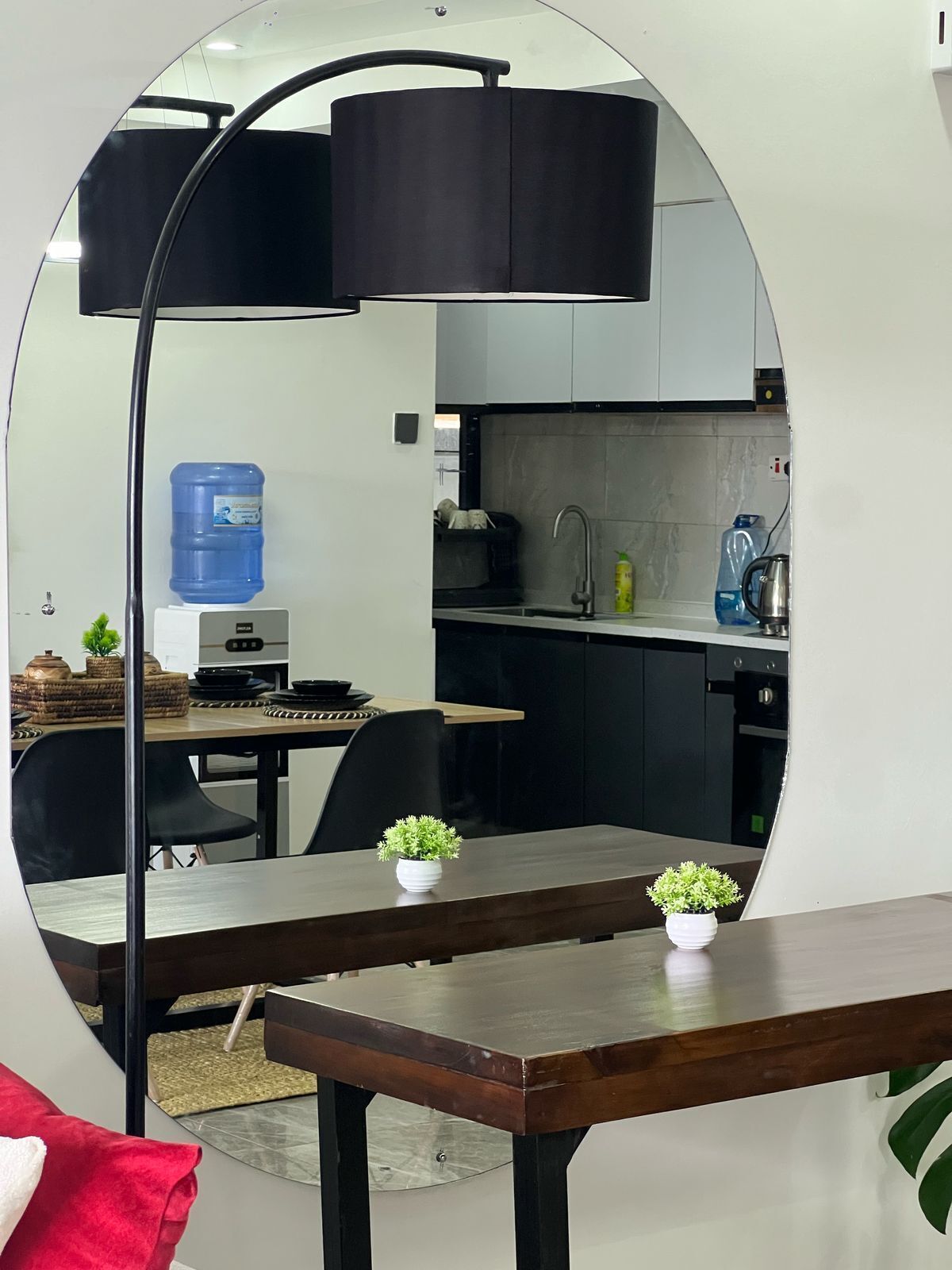 A modern kitchen with a water dispenser, a sink, and a kettle. There is a dining area with a table and chairs.