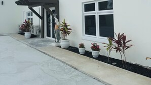A two-story building with a covered entrance, potted plants, and a clear sky. - Bella Signature Suites  (Nassau)