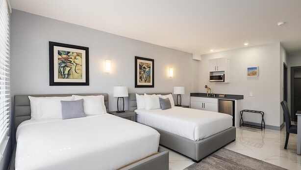 A modern hotel room with two beds, a desk, and a bathroom. - Bella Signature Suites  (Nassau)