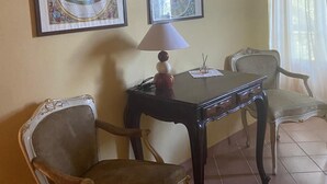 Una stanza con un tavolo da pranzo, due sedie, una lampada e quattro opere d'arte incorniciate appese al muro.
