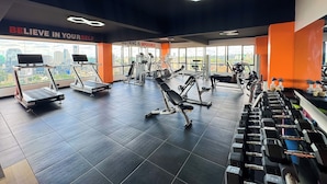 A gym with treadmills, weight machines, and dumbbells.