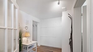 A hallway with a white desk, a lamp, a plant, and a door with a coat rack.