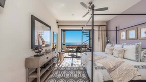 Ein Schlafzimmer mit Bett, Schreibtisch, Stuhl und Meerblick.
