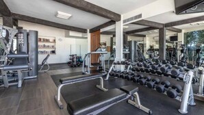 Ein Fitnessstudio mit verschiedenen Trainingsgeräten, darunter Laufbänder, Kurzhanteln und Kraftgeräte.