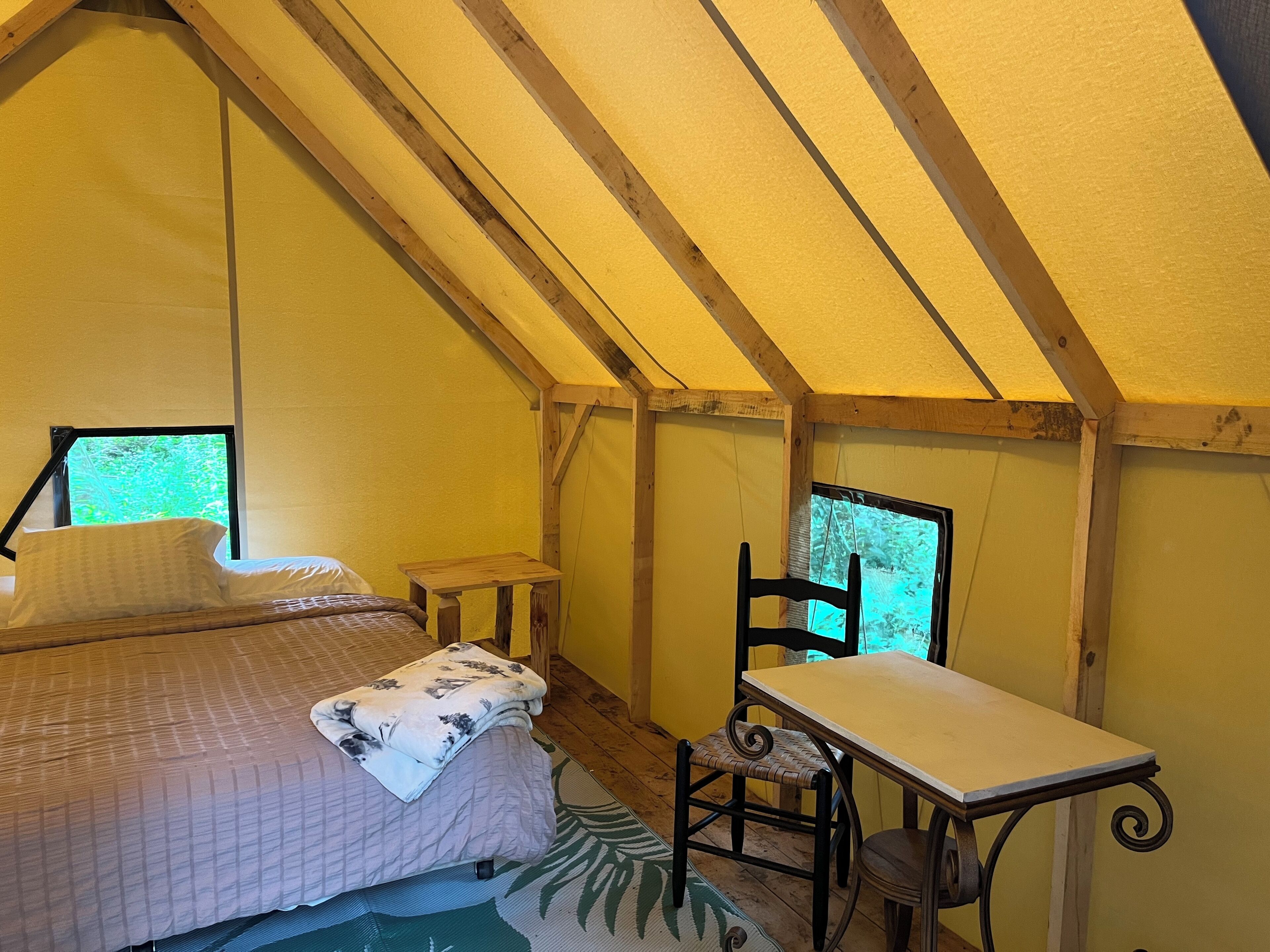 A cozy attic bedroom with a bed, a small table, and a chair.