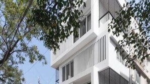 Um edifício moderno com portão fechado, número 21, e uma scooter estacionada.