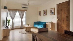 Uma sala de estar moderna com uma mesa de jantar de madeira, um sofá azul e um armário de madeira.