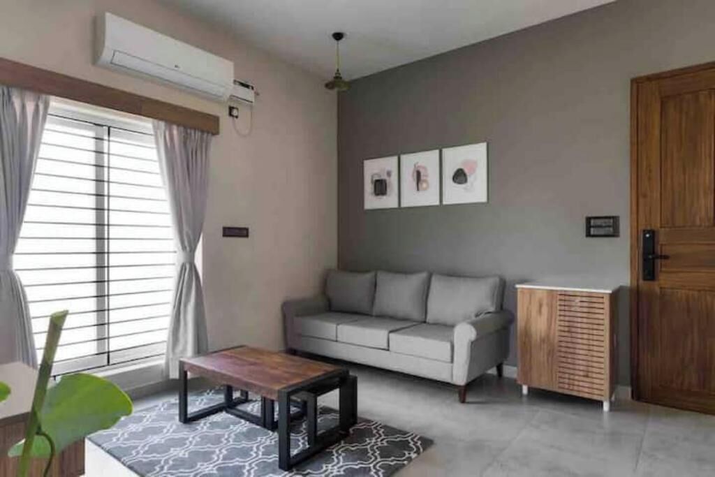 Una sala de estar con un sofá gris, una mesa de centro de madera y una alfombra gris estampada.