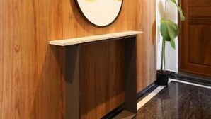 A wooden wall with a circular mirror and a small shelf.