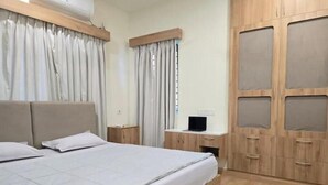 A bedroom with a bed, a nightstand, a desk, and a wardrobe.