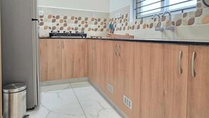 A kitchen with wooden cabinets, a gas stove, a window with blinds, and a tiled backsplash.