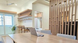 A modern dining area with a wooden table, chairs, and a laptop.
