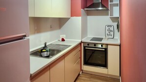 Eine kleine Küche mit Kühlschrank, Backofen und einer Pendelleuchte.