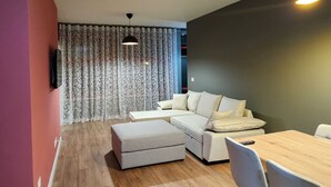 Ein modernes Wohnzimmer mit einer Eckcouch, einem Esstisch mit Stühlen und Holzboden.