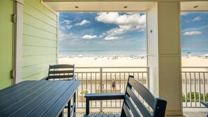 Un balcon donnant sur une plage, avec une table et deux chaises.