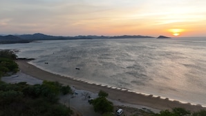 Een strand met boten, een zandstrand en bergen in de verte.