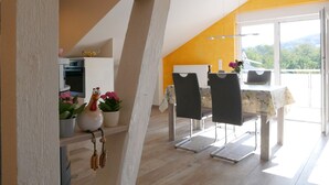 A dining area with a table and chairs, a white radiator, and a view of greenery outside. - Apartment 'Kirschblüte' (Achern)